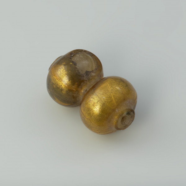 paciorek , biżuteria - Ujęcie przodu paciorka skosem w prawą stronę. Paciorek szklany dwusegmentowy zdobiony złotą folią.