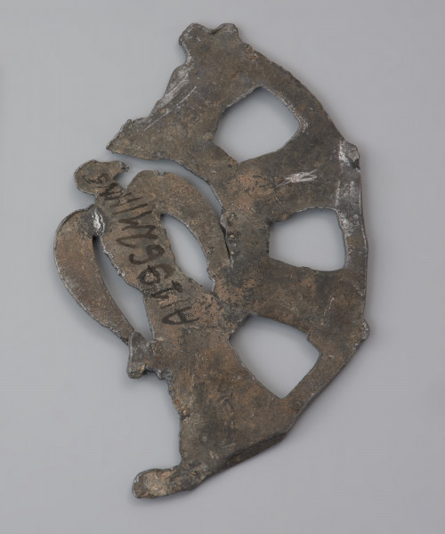 plakietka ażurowa z ptakiem - Ujęcie odwrocia . Metalowa, okrągła plakietka ażurowa z wyobrażeniem ptaka w części centralnej. Na odwrocie znajdują się haczyki do przypinania ozdoby do odzieży.