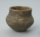 Jasnobrunatne naczynie gliniane o niskiej, przysadzistej formie - Ujęcie z tyłu. Jasnobrunatne naczynie gliniane o niskiej, przysadzistej formie.