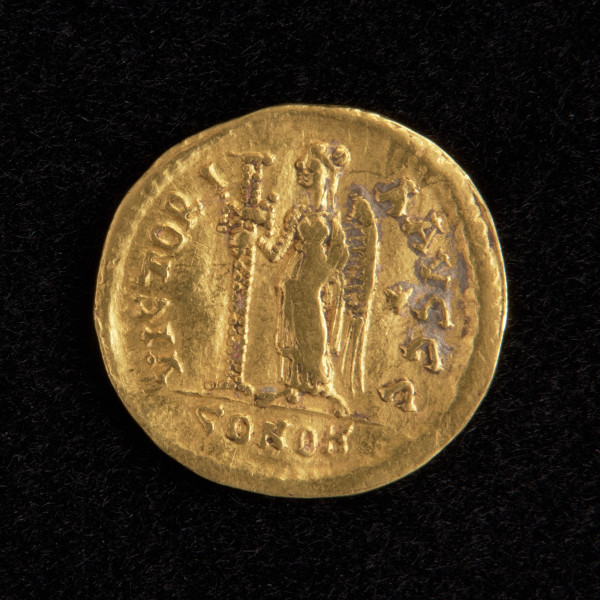 moneta - Ujęcie rewersu. Na rewersie widnieje stojąca skrzydlata postać Victorii zwrócona w prawo. W prawej ręce trzyma długi ozdobny krzyż. Po jej lewej stronie widnieje sześcioramienna gwiazda. Wokół wizerunku znajduje się napis VICTORIA AUGGG, a pod stopami CONOB.