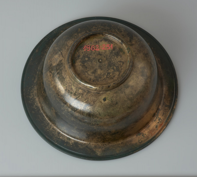 Rzymska miseczka z brązu na stopce - Ujęcie z dołu. Rzymska miseczka z brązu na stopce z cylindrycznym brzuścem, szerokim wygiętym na zewnątrz wylewem, posrebrzana wewnątrz.