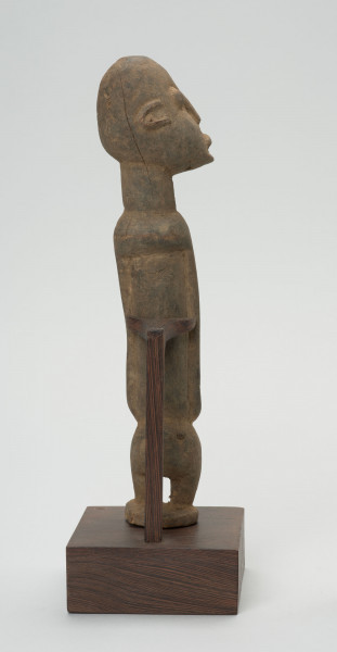 rzeźba - Ujęcie z tyłu; Figura - postać przodka. Głowa i korpus w stosunku do nóg bardzo duże - co typowe jest dla sztuki dogońskiej. Głowa zwrócona w prawą stronę. Widoczne pęknięcie rzeźby wzdłuż głowy tuż za uchem.