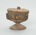 naczynie, rzeźba - Ujęcie z przodu. Drewniane, okrągłe naczynie o kształcie kielichowym na krótkiej, okrągłej nóżce z przykrywką. Całość ozdobiona wzorami geometrycznymi w postaci płytkich nacięć.