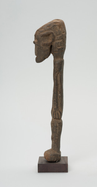 rzeźba - Ujęcie prawego boku. Figurka przedstawiająca postać ludzką. Głowa bardzo duża, reszta sylwetki schematyczna, bardzo smukła, lekko wygięta w prawą stronę. Włosy zaznaczone ciosanymi rytami. Nogi wąskie, złączone.