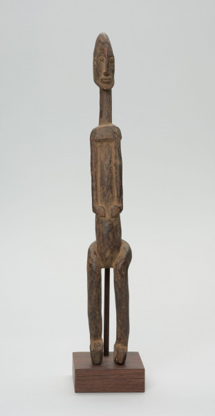 rzeźba - Ujęcie z przodu; Figura - postać przodka. Figura antropomorficzna, sylwetka smukła, wydłużona. Ręce krótkie, dłonie ułożone nad pępkiem. Twarz schematyczna w stylu dogońskim. Szerokie biodra. Związana z kultem przodków.