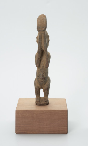 rzeźba - Ujęcie z przodu. Figura - postać mężczyzny w pozycji stojącej z ugiętym kolanami. Ręce i dłonie nieproporcjonalnie długie/duże w stosunku do całej postaci. Ręce zakrywają twarz, dłonie sterczą ponad głową. Rzeźba przeznaczona na ołtarz przodków.