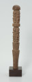 drewniana, rzeźbiona pałka - Ujęcie z tyłu. Okrągła, drewniana pałka z płytko rzeźbionymi dwoma rzędami postaci ludzkich. W każdym rzędzie zaznaczonych zostało czterech przodków, bez wyraźnie zaznaczonych cech płciowych.
