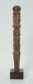 drewniana, rzeźbiona pałka - Ujęcie z prawego boku. Okrągła, drewniana pałka z płytko rzeźbionymi dwoma rzędami postaci ludzkich. W każdym rzędzie zaznaczonych zostało czterech przodków, bez wyraźnie zaznaczonych cech płciowych.