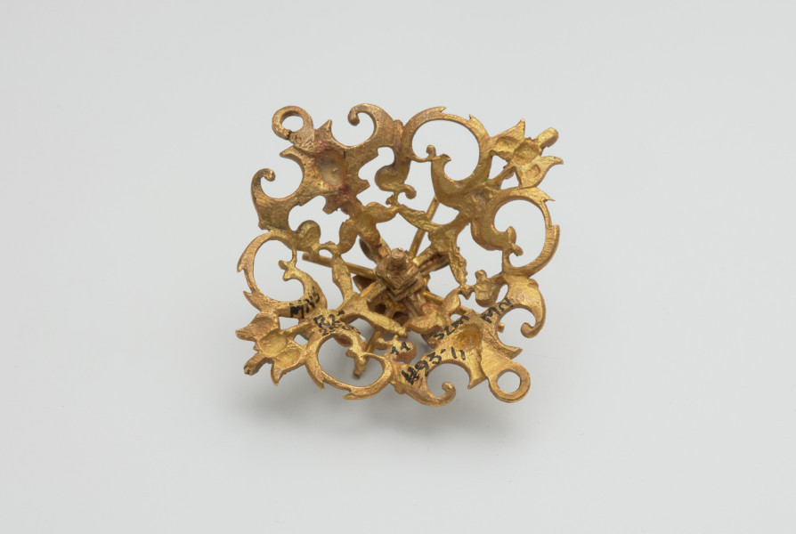 biżuteria, ozdoby - Ujęcie spodu klejnotu. Ażurowy klejnot z kołpaka z diamentem i - pierwotnie -czterema perłami, zdobiony barwną emalią.