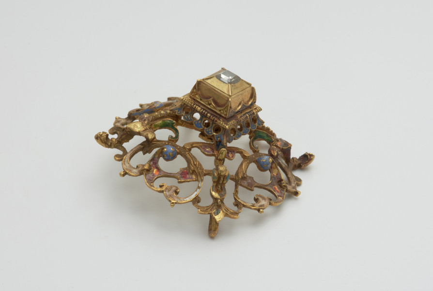 biżuteria, ozdoby - Ujęcie w pionie z przodu skosem w prawą stronę. Ażurowy klejnot z kołpaka z diamentem, zdobiony barwną emalią.