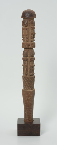 drewniana, rzeźbiona pałka - Ujęcie z przodu. Okrągła, drewniana pałka z płytko rzeźbionymi dwoma rzędami postaci ludzkich. W każdym rzędzie zaznaczonych zostało czterech przodków, bez wyraźnie zaznaczonych cech płciowych.