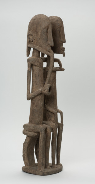 rzeźba - Ujęcie przodu i boku z lewej strony; Figura - para przodków -  mężczyzny i kobiety. Oboje ujęci w pozycji siedzącej. Postacie smukłe. Mężczyzna w ustach ma fajkę, obejmuje lewą ręką kobietę. Związana z kultem przodków.