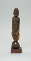 rzeźba - Ujęcie z przodu. Figura przedstawiająca postać przodka -  mężczyznę ze skrzyżowanymi nogami. Figura antropomorficzna, oddająca cechy dogońskiego kanonu przedstawiania ludzi.