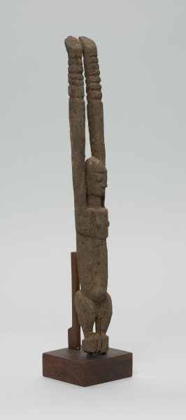 rzeźba - Ujęcie z przodu z prawej strony. Figura antropomorficzna przedstawiająca postać z rękoma wyciągniętymi do góry. Ręce nieproporcjonalnie długie.
