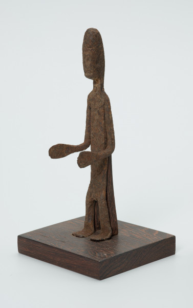 rzeźba - Ujęcie przodu skosem w lewą stronę. Figurka - postać mężczyzny. Zarysowana tylko sylwetka, ugięte kolana, Ręce zgięte w łokciach. Stanowi wyposażenie grobu.