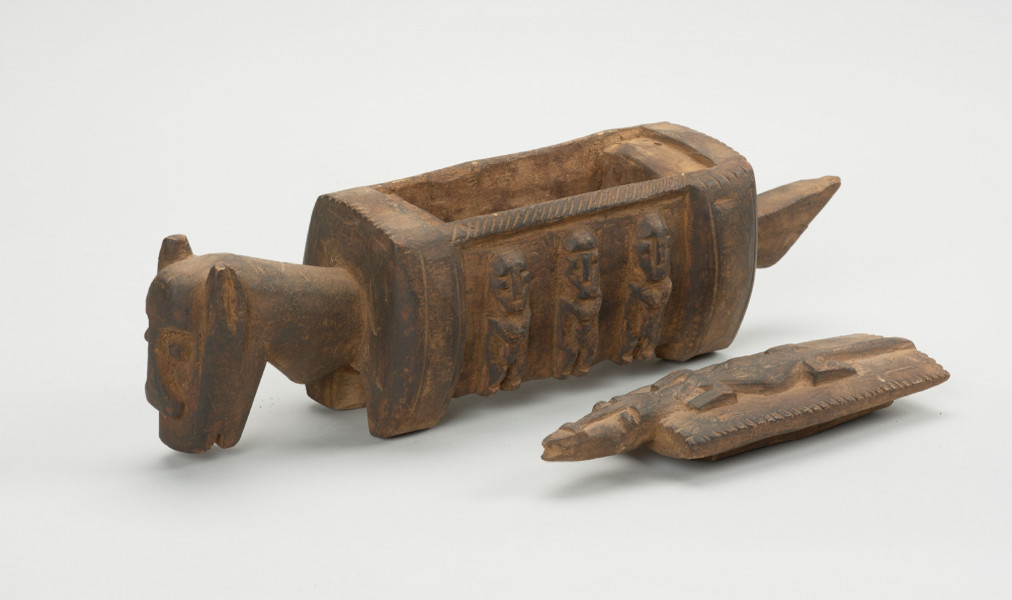 rzeźba - Ujęcie przodu i boku; Arka Nommo zwana inaczej aduno koro lub arką świata, jest wyobrażeniem mitycznej łodzi. Rozłozony drewniany zdobiony obiekt na część a i b. Część a - większa, wyglądem przypominająca konia z tułowiem jako transport do przewożenia. Bok z płaskorzeźbą na ktorej widnieją 3 postacie ustawione w rzędzie. Druga część oiektu, część b- Mała płaskorzeźba przypominająca jaszczurkę lub krokodyla z prostokątnym tułowiem.