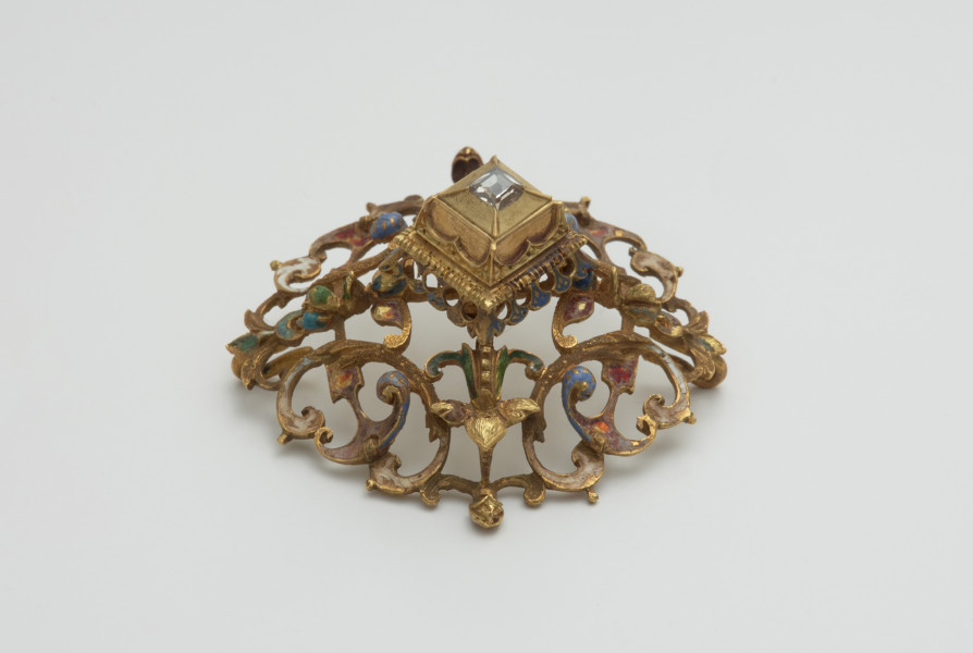 biżuteria, ozdoby - Ujęcie w pionie tyłu. Ażurowy klejnot z kołpaka z diamentem, zdobiony barwną emalią.