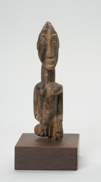 rzeźba - Ujęcie z przodu. Figura przedstawiająca postać kobiety. Duża głowa, z zaznaczoną fryzurą, ręce prostymi cięciami wydobyte z tułowia. Figura kanoniczna. Brak nóg. Związana z kultem przodków.