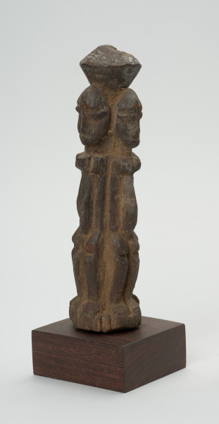 rzeźba - Ujęcie tyłu skosem w lewą stronę. Drewniana rzeźba czterech postaci zwróconych do siebie plecami. Każdy z nich zwrócony jest w inną stronę świata. Postaci wyrzeźbione schmeatycznie. Zarysowana duża, podłużna głowa, szczupłe ramiona, tułów, krótkie nogi ugięte w kolanach.