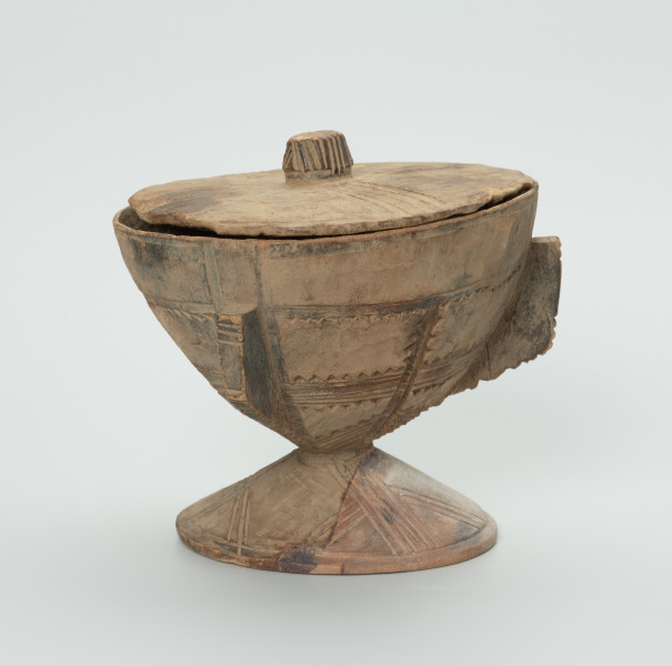naczynie, rzeźba - Ujęcie z tyłu. Drewniane, okrągłe naczynie o kształcie kielichowym na krótkiej, okrągłej nóżce z przykrywką. Całość ozdobiona wzorami geometrycznymi w postaci płytkich nacięć.