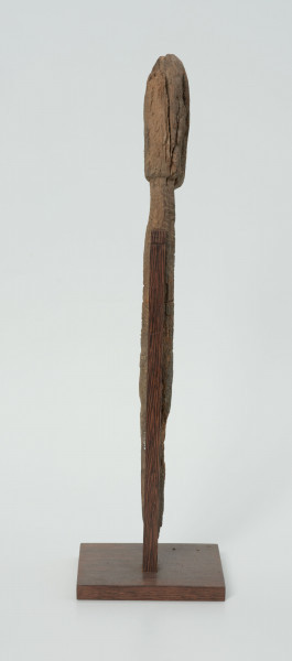 Ujęcie z tyłu; Rzeźba. Figura - Nommo - drewniana pałka zakończona głową o cechach antropomorficznych. Rzeźba umieszczona na drewnianej podstawie.