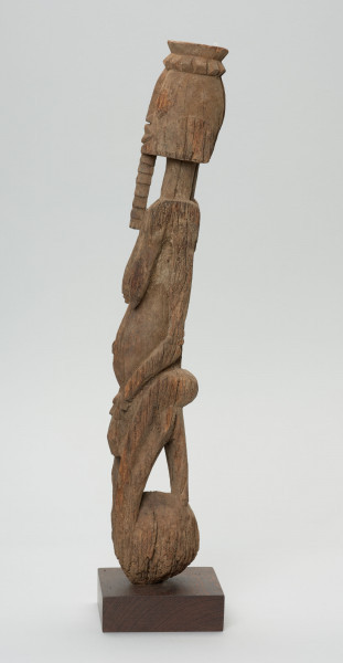 rzeźba - Ujęcie z prawego boku; Figura - postać kobiety  - przodka, obdarzona została bowiem ozdobną brodą, czyli pewną cechą męską. Głowa i korpus oddzielone od szyi prostymi cięciami. Oczy duże wypukłe, piersi długie, płaskie, nogi zatarte w wyniku używania. Związana z kultem przodków.