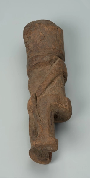 Drewniana figurka mężczyzny z dużą głową - Ujęcie prawej strony w poziomie. Drewniana figurka mężczyzny w pozycji stojącej. Głowa nieproporcjonalnie duża, cała forma uproszczona. Sylwetka masywna.
