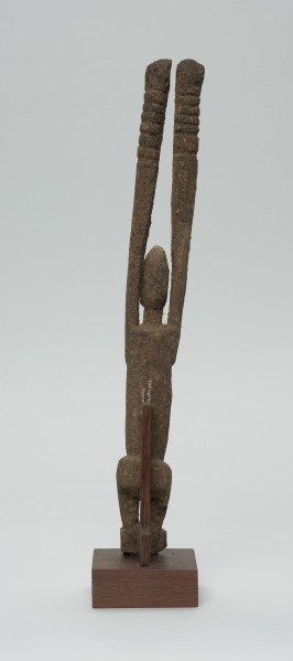 rzeźba - Ujęcie z tyłu. Figura antropomorficzna przedstawiająca postać z rękoma wyciągniętymi do góry. Ręce nieproporcjonalnie długie.