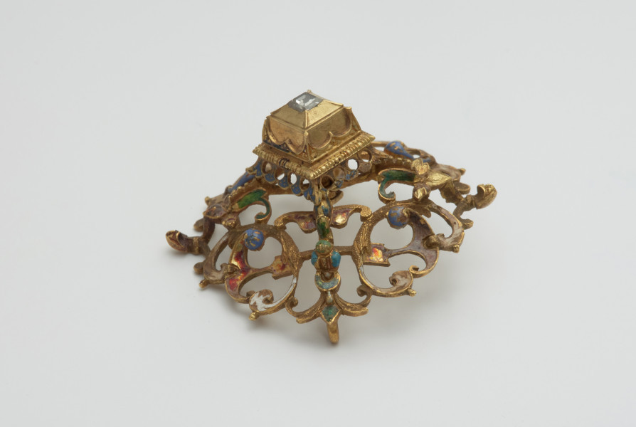 biżuteria, ozdoby - Ujęcie z góry przodu skosem w lewą stronę. Ażurowy klejnot z kołpaka z diamentem, zdobiony barwną emalią.