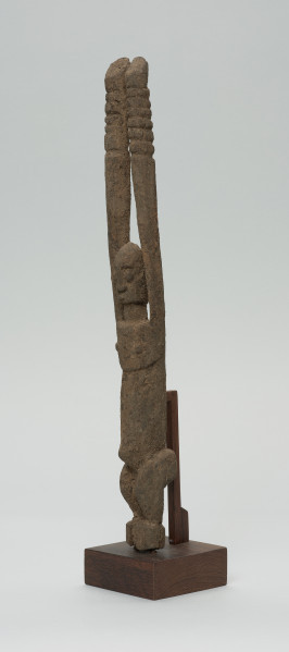 rzeźba - Ujęcie z przodu z lewej strony. Figura antropomorficzna przedstawiająca postać z rękoma wyciągniętymi do góry. Ręce nieproporcjonalnie długie.