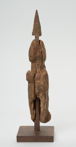 rzeźba - Ujęcie z tyłu skosem w prawą stronę. Uproszczona postać ludzka, z wetkniętym grotem strzały. Na wysokości nogi widnieje numer inwentarzowy. Rzeźba stanowi część wyposażenia grobu.