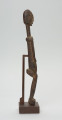 rzeźba - Ujęcie z lewego boku; Figura - postać przodka. Figura antropomorficzna, sylwetka smukła, wydłużona. Ręce krótkie, dłonie ułożone nad pępkiem. Twarz schematyczna w stylu dogońskim. Szerokie biodra. Związana z kultem przodków.