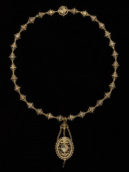 odznaka honorowa elektora saskiego Jana Jerzego I - Ujęcie odznaki z przodu z łańcuchem. Odznaka o owalnym kształcie, ażurowa, emaliowana. Jej głównym elementem jest czarny dwugłowy orzeł w koronie cesarskiej. Na awersie, na piersi orła herb Saksonii Elektorskiej. W owalnej ramce, otoczonej rucianym wieńcem inskrypcja: SVB. VMBRA. ALARUM. TUARUM.1.6.11. Na rewersie na tułowiu orła wieniec z kwiatkami trzymany przez dwie dłonie. W otoku napis: PRVS. MOR. QVAM. FIDEM. FALLIERE. U dołu szczątkowo zachowana perła. Odznaka przy pomocy trzech łańcuszków połączona jest z ażurową plakietką z uszkiem. Łańcuch składa się z dziesięciu owalnych ogniw z emaliowanymi herbami prowincji saskich (różnymi po obu stronach). Między nimi ogniwa z motywem dłoni trzymających zielony wieniec z białymi kwiatkami, a także gładkie okrągłe ogniwa i ogniwa o fakturze plecionki. Na emaliowanej, kolistej zapince motyw dwugłowego orła z herbem Saksonii Elektorskiej.