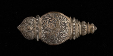 MNS/Rz/2222/2 okucie końca pendentu księcia Kazimierza VI/IX (1557-1605) - Ujęcie z przodu. Okucie końca pendentu o migdałowym kształcie, u góry w przewężeniu profilowana przepaska, nad nią zwieńczenie w kształcie łuku w ośli grzbiet. Dolna część profilowana, o trójkątnym zarysie. Okucie w całości pokryte grawerowaną, niellowaną dekoracją z motywem ptaka wśród wici roślinnej, stylizowanych kwiatów i ornamentów ciągłych. W górnej części, pośrodku łuku w ośli grzbiet - okrągły otwór z nitem.