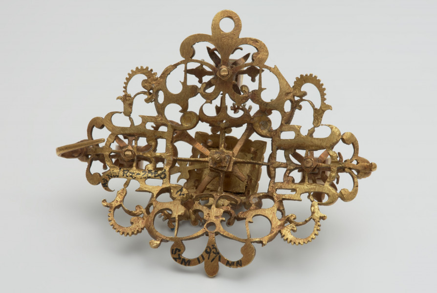 nakrycia głowy, biżuteria, ozdoby - Ujęcie z tyłu. Klejnot z kołpaka w kształcie rombu, ażurowy, zdobiony emalią i kasztami z diamentami.