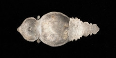 okucie końca pendentu księcia Kazimierza VI/IX (1557-1605) - Ujęcie z tyłu. Okucie końca pendentu o migdałowym kształcie, u góry w przewężeniu profilowana przepaska, nad nią zwieńczenie w kształcie łuku w ośli grzbiet. Dolna część profilowana, o trójkątnym zarysie. Okucie w całości pokryte grawerowaną, niellowaną dekoracją z motywem ptaka wśród wici roślinnej, stylizowanych kwiatów i ornamentów ciągłych. W górnej części, pośrodku łuku w ośli grzbiet - okrągły otwór z nitem.
