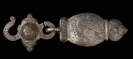 Zapinka pendentu (3części), księcia Kazimierza VI/IX (1557-1605) - Ujęcie prawej części sprzączki. Sprzączka pasa składająca się z trzech elementów. Dwa skrajne o migdałowym kształcie, z jednej strony zakończone profilowanym przewężeniem i łukiem w ośli grzbiet, z drugiej mają przylutowane poprzecznie koliste uszka z gładkiego drutu. Środkowy element sprzączki,zdobiony jest guzem ujętym od góry i dołu profilowanymi sterczynami; po prawej stronie uszko, którym połączony jest z bocznym elementem zapinki, a po lewej - esowato wygięty haczyk, służący do zapinania pasa. Wszystkie części zapinki pokryte są gęsto grawerowaną, niellowaną dekoracją z motywami ptaków wśród wici roślinnej oraz stylizowanych kwiatów i ornamentem geometrycznym.
