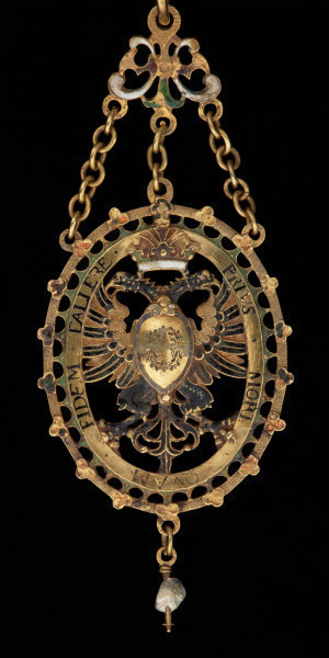 odznaka honorowa elektora saskiego Christiana II - Ujęcie medalu z przodu. Odznaka o owalnym kształcie, ażurowa, emaliowana. Na awersie pośrodku tarcza migdałowa z elektorskim herbem dzielonym. W otaczającym ją ornamencie na dwóch tabliczkach dewiza: A DEO / PRO IMPERIO. Nad inskrypcją oko opatrzności. Na rewersie w środkowym polu motyw słońca w otoczeniu sześciu gwiazd. Na tabliczkach inskrypcja: „TIME DEUM / HONORA CAESAREM”. U dołu zawieszenia sztyft będący pozostałością po perle. Odznaka przy pomocy trzech łańcuszków połączona jest z ażurową plakietką z uszkiem. Łańcuch składa się z 30 ozdobnych, ażurowych, emaliowanych ogniw, połączonych kółkami ze złotego drutu. Na połowie z nich ukazano emaliowane herby 15 prowincji saskich. Na pozostałych 15 przedstawiono serce z literą C i kapeluszem elektorskim, trzymane w dwóch dłoniach. Na kolistej zapince emaliowany herb elektorskiej Saksonii.