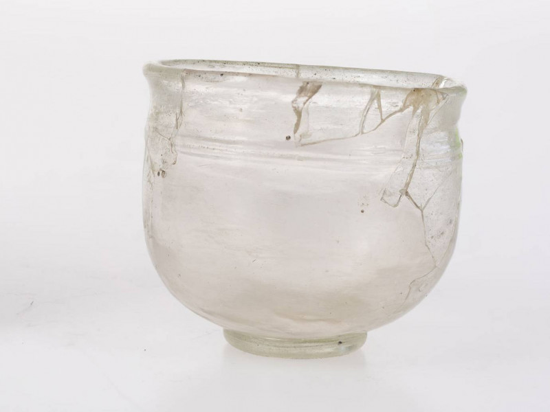 Naczynie szklane w formie pucharka na pierścieniowatej stopce. Stopka dolepiana ze śladem przylepca. Wylew wychylony o zaokrąglonej krawędzi. Pod wylewem znajduje się pozioma nitka obiegająca korpus 1,5 raza. Brzusiec zaokrąglony przechodzący w płaską część przydenną. Naczynie określane jako 