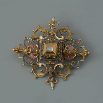 rozeta z kołpaka księcia Filipa II (1573-1618) - Ujęcie z przodu. Klejnot zbudowany z dwóch skręconych ze sobą śrubą części: ażurowego stelaża o romboidalnym kształcie i osadzonej na nim wysokiej, kasetowej oprawy, ujmującej diament o szlifie tablicowym. Stelaż i ścianki kasztu pokryte barwną emalią, korpusową, a także żłobkową, z wzorami rezerwowanymi w złocie. Rozety mają na spodniej stronie, w narożach, haczyki umożliwiające spinanie ich w łańcuch, a także uszka pozwalające na ich mocowanie do stroju.