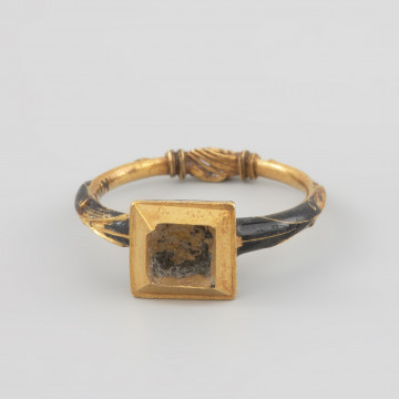 pierścień ślubny księcia Franciszka I (1577 - 1620) - Ujęcie z przodu. Pierścień, pierwotnie z diamentem, umieszczonym w kaszcie o prostokątnym przekroju, zaokrąglonym od spodu. Szyna pierścienia zwężająca się ku końcowi, zakończona jest plastycznym przedstawieniem splecionych dłoni. Ścianki spodniej części kasztu i zewnętrzna strona obrączki pokryte czarną emalią ze złotym ornamentem.