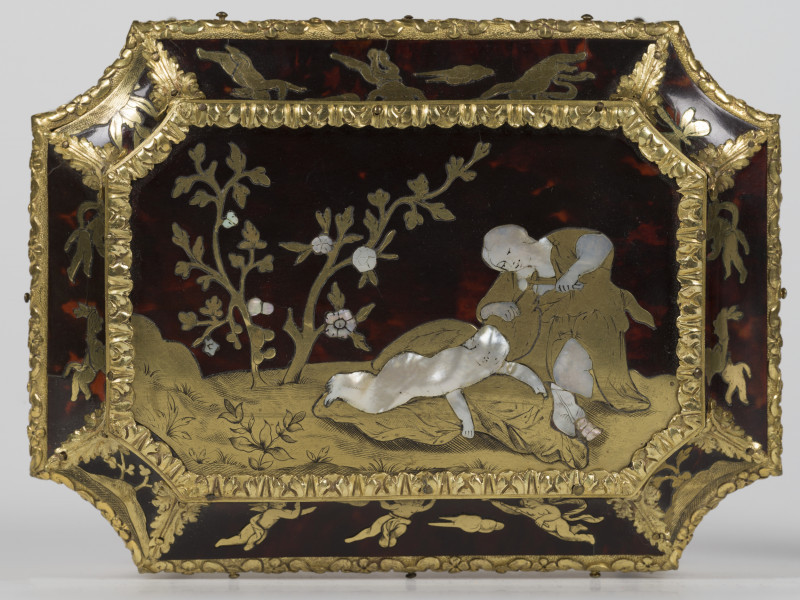 zbliżenie na dekorację wieka - Wenus przecina skrzydła Amorowi, widok od góry w tle motywy roślinne, krawędzie wieka pokryte dekoracjami z brązu w postaci palmet i ornamentu kwiatowego.