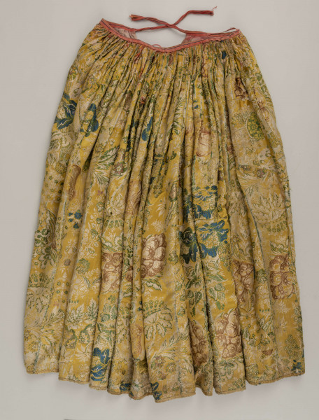E/880/ML - Spódnica wykonana z brokatu, różnobarwna w kwiaty. Przewaga koloru złotego. Posiada lnianą podszewkę. Na przodzie wstawione lniane płótno w pasy. Noszona przez zamężne kobiety, bogate mieszczki tarnogrodzkie.