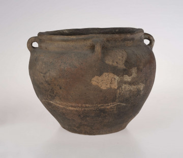 Baniaste naczynie z czterema uszkami o brunatnej powerzchni. Dno niewyodrębnione, delikatnie wklęsłe. Szyjka krótka, cylindryczna.