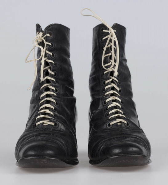 E/11811/ML - Buty odświętne, z czarnej licowej skóry. Wewnątrz płócienna podszewka. Obcas słupowaty wys. 5 cm. Podeszwy ze skóry. Cholewka wys. 10 cm, dopasowana do nogi, z przodu sznurowana. Nosek zwężony, na końcu ścięty. Wykrój podeszew w obu butach identyczny – lewy równa się prawemu.