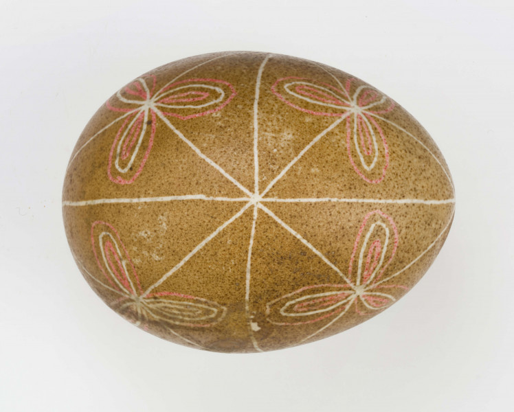 Technika batik. Podział podłużny na 4 części, podział poprzeczny na 2 części. Motyw trikwert. Barwa tła brązowa, barwa motywu biała i czerwona.