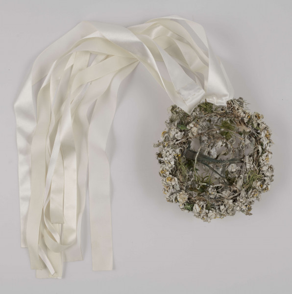 E/527/ML - Strój głowy w formie wianka. Na konstrukcji z drutu napięte są białe płócienne kwiaty, zielone listki oraz przypiete sa białe wstążki. Wianek noszony przez panny młode.
