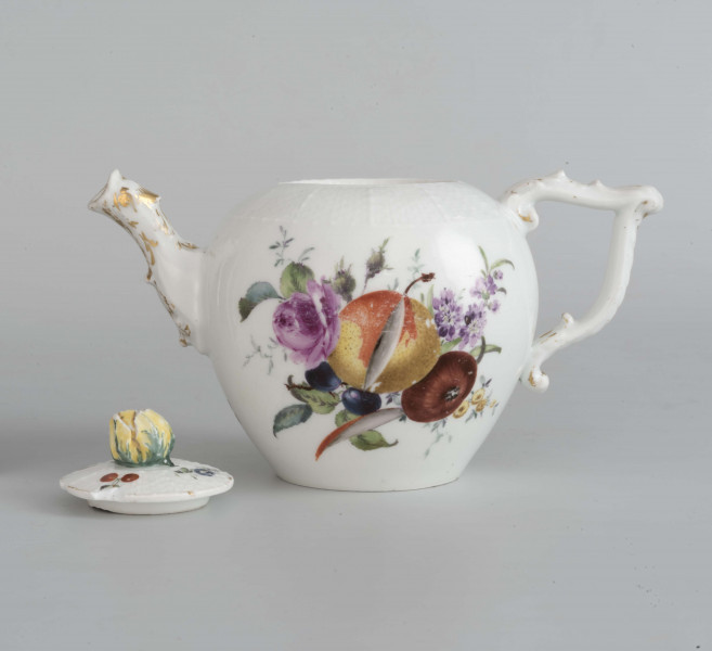 Imbryk kulisty lekko zwężony ku dołowi, wokół wylewu zdobiony plastyczną plecionka w typie Alt-Ozier. Dziobek rurkowy zakończony rozwartym smoczym pyskiem podkreślonym plastycznym liściem akantu. Ucho rokokowe w kształcie litery 