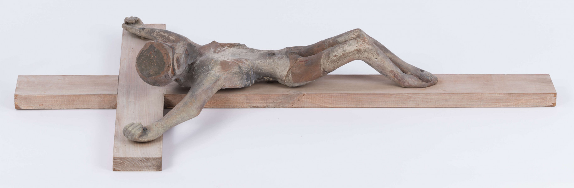 E/367/ML - Rzeźba w glinie przedstawiająca Chrystusa Ukrzyżowanego. Głowa schylona lekko w prawa stronę. Ciało nagie. Nogi podkulone i przebite żelaznym gwoździem. Glina wypalona.