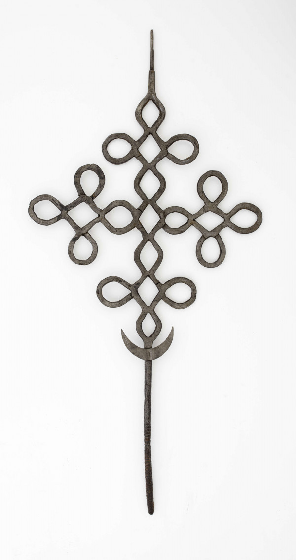 Krzyż o ramionach wykonanych z płaskich prętów żelaznych, powyginanych w ten sposób, że tworzą małe krzyżyki. W dolnej części krzyża przynitowany półksiężyc. Dolny koniec środkowego ramienia w postaci obłego pręta.